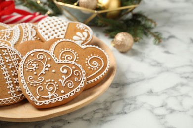 Photo of Tasty heart shaped gingerbread cookies on white marble table, closeup. Space for text