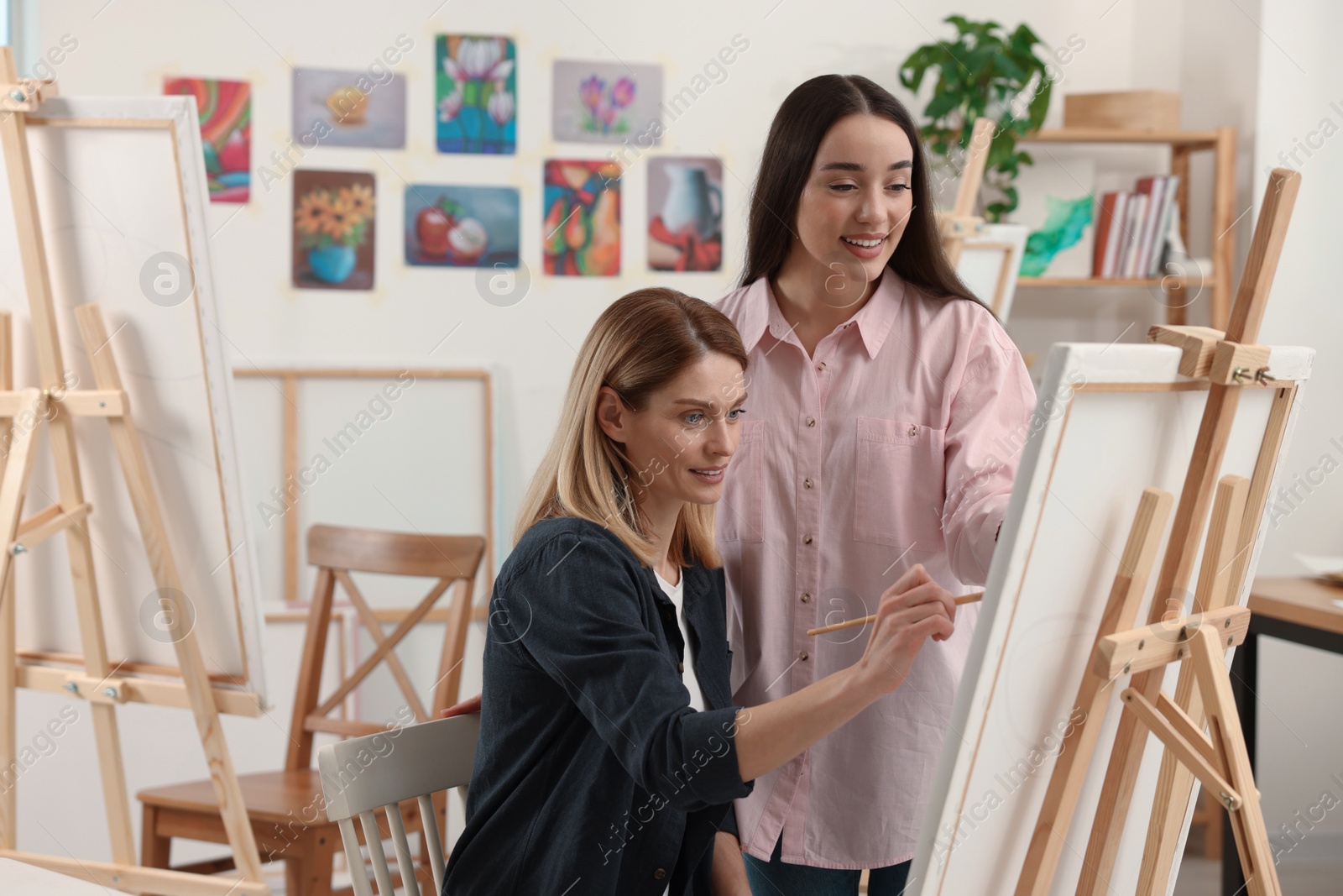 Photo of Artist teaching her student to paint in studio. Creative hobby