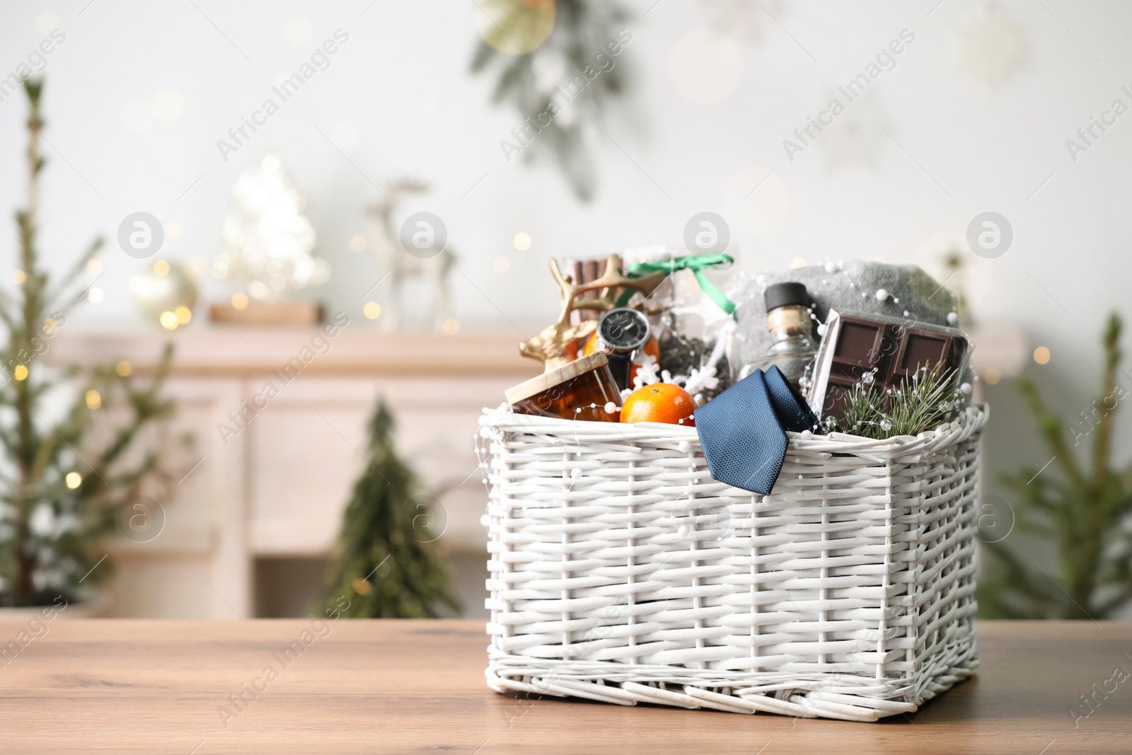 Photo of Wicker basket with Christmas gift set on wooden table. Space for text