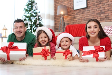 Happy parents and children with gifts near Christmas tree at home