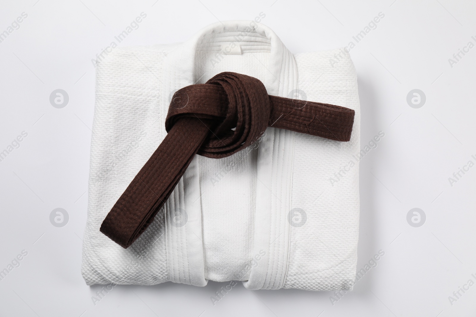 Photo of Brown karate belt and kimono on white background, top view