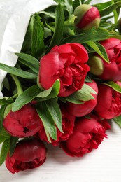 Photo of Beautiful bouquet of red peony flowers on white wooden table, closeup