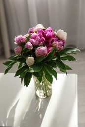 Photo of Vase with bouquet of beautiful peonies on table in room