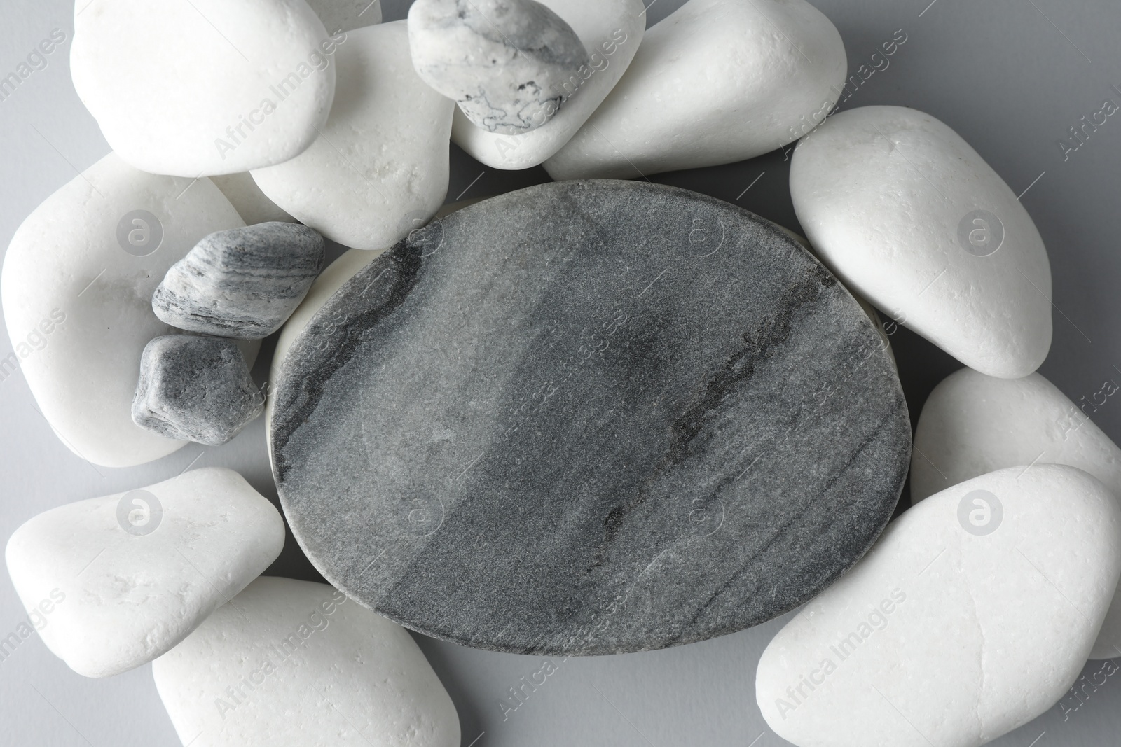 Photo of Presentation for product. Stone podium and pebbles on light grey background, top view