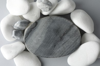 Photo of Presentation for product. Stone podium and pebbles on light grey background, top view