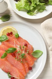 Photo of Delicious salmon carpaccio served on white wooden table, flat lay