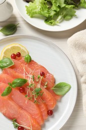 Delicious salmon carpaccio served on white wooden table, flat lay