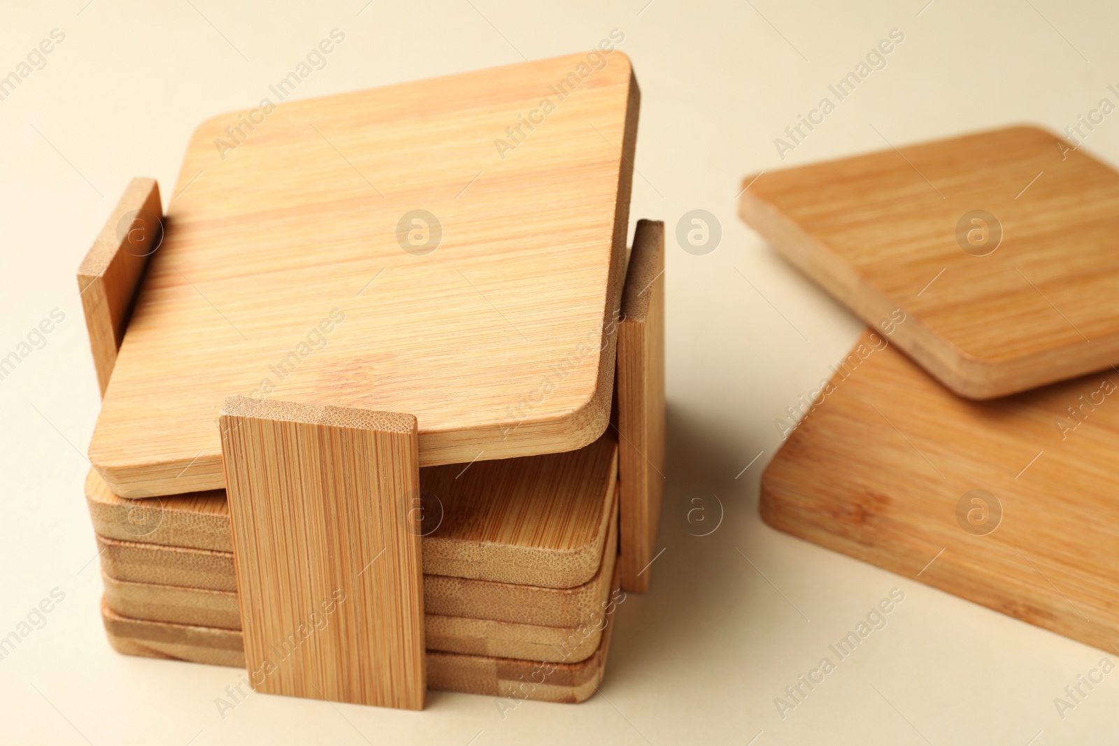 Photo of Stylish wooden cup coasters and holder on beige background