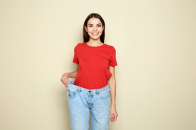 Photo of Slim woman in oversized jeans on color background. Weight loss