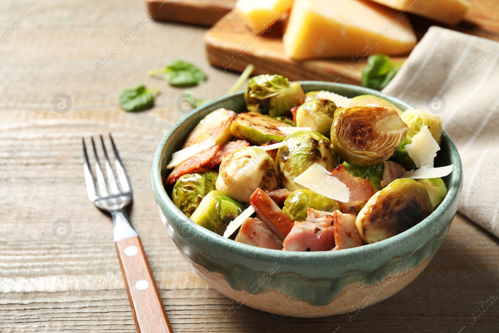 Image of Delicious fried Brussels sprouts with bacon in bowl on wooden table