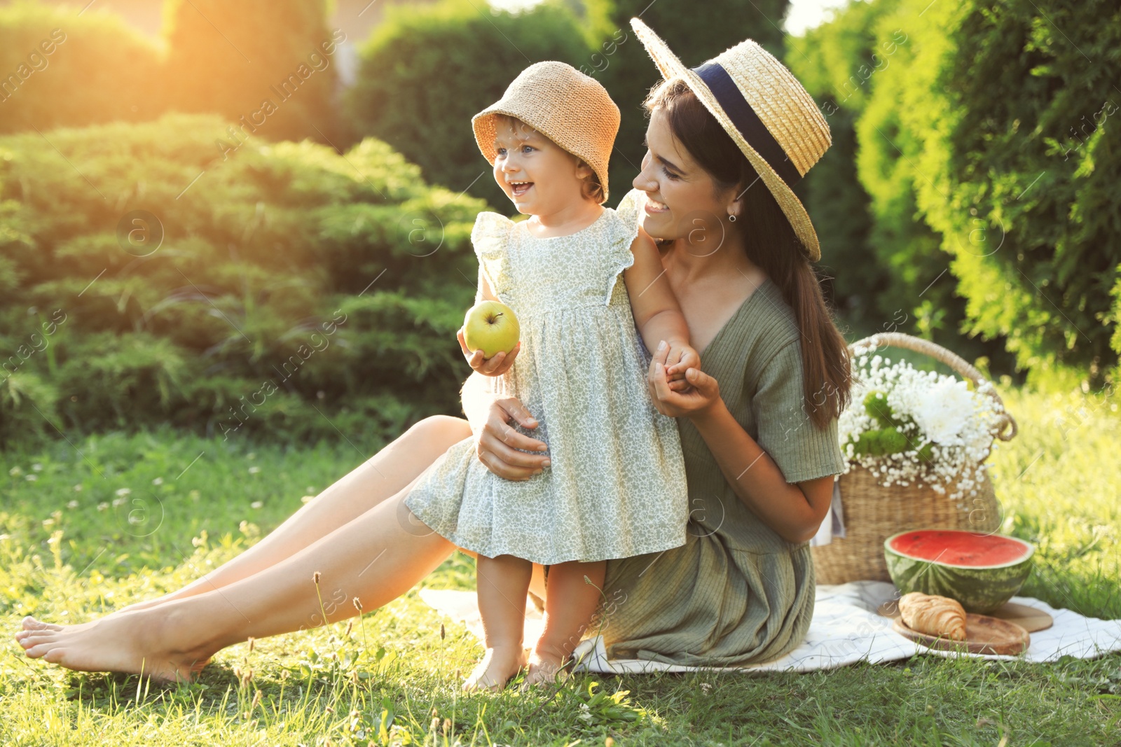 Photo of Mother with her baby daughter having picnic in garden on sunny day