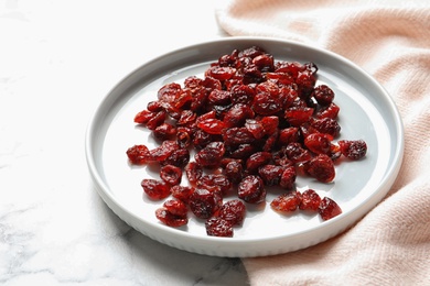 Photo of Plate with cranberries on marble table. Dried fruit as healthy snack