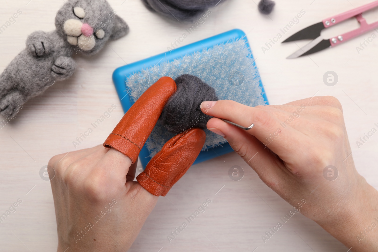 Photo of Woman felting from wool at light wooden table, top view