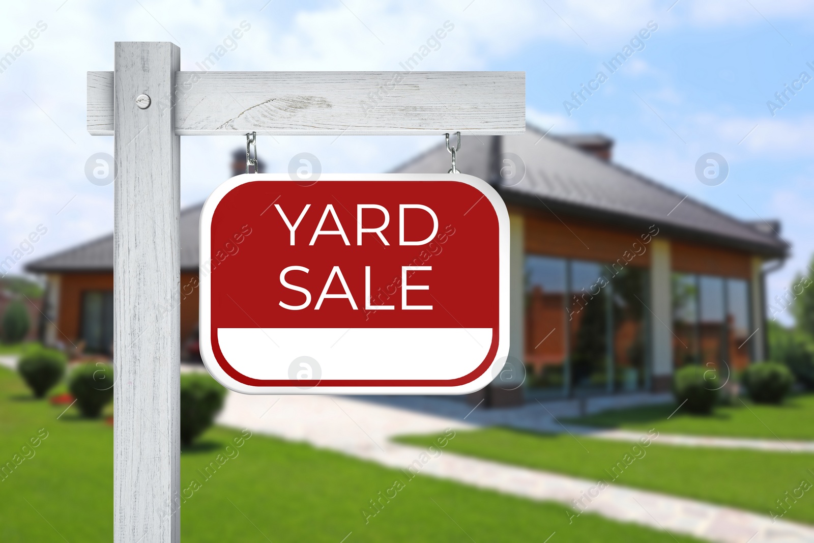 Image of Sign with text YARD SALE and blurred view of modern house on sunny day