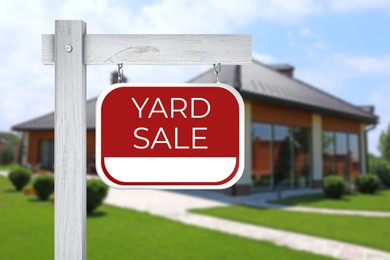 Image of Sign with text YARD SALE and blurred view of modern house on sunny day