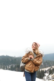 Photo of Young woman in warm clothes near snowy hill. Winter vacation