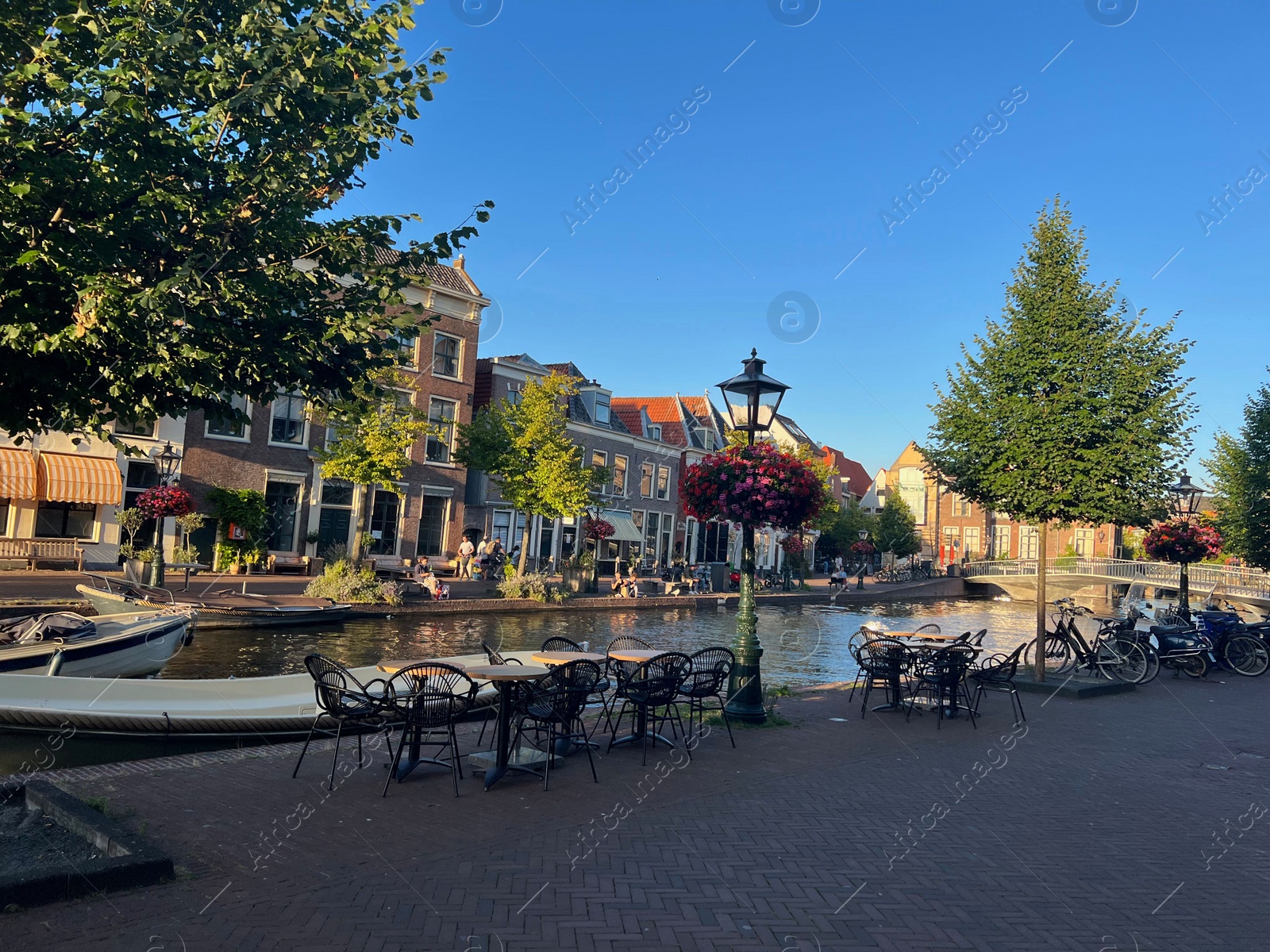 Photo of Leiden, Netherlands - August 1, 2022: Picturesque view of city street with cafe and beautiful buildings along canal