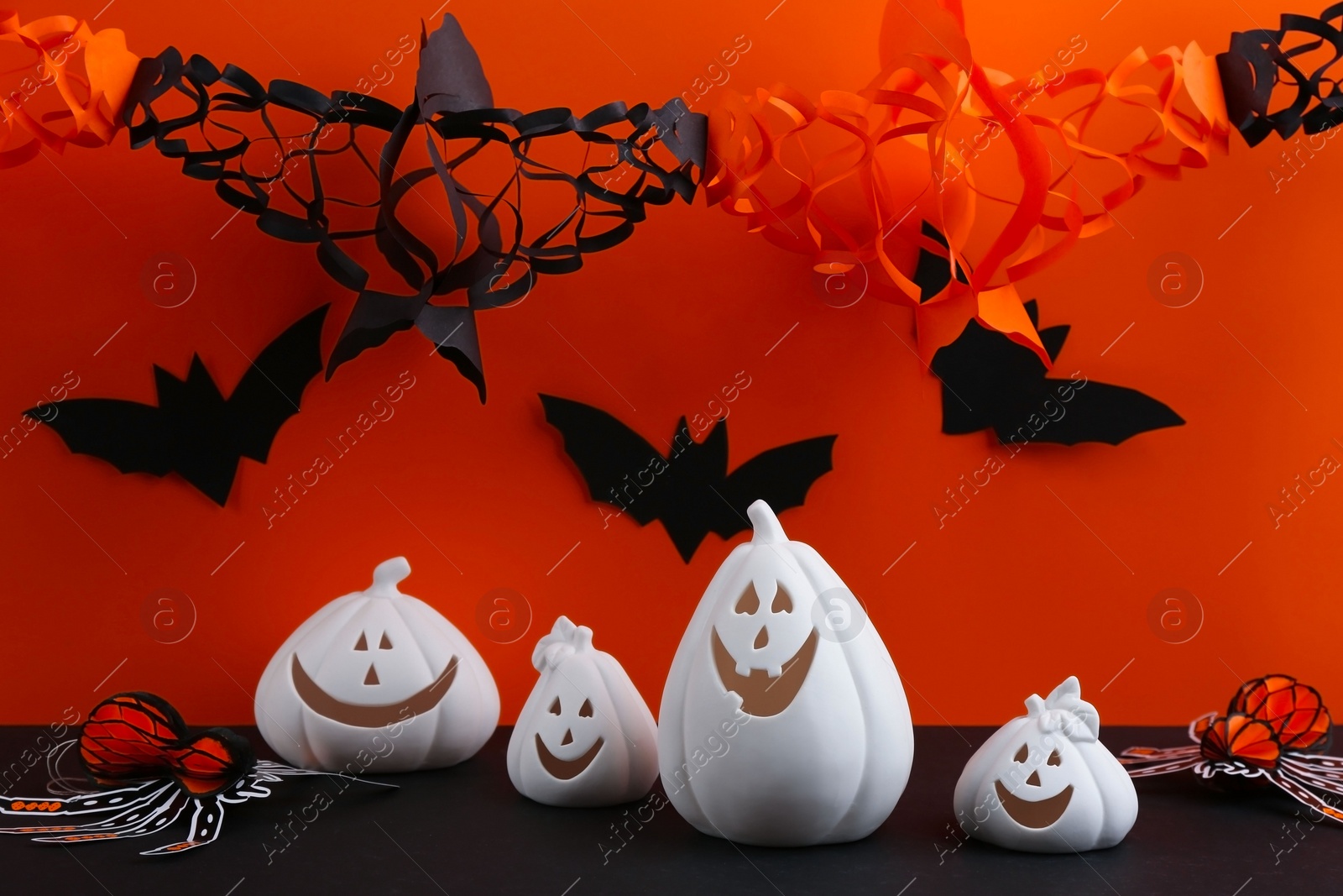 Photo of Composition with pumpkin shaped candle holders on black table. Halloween decoration