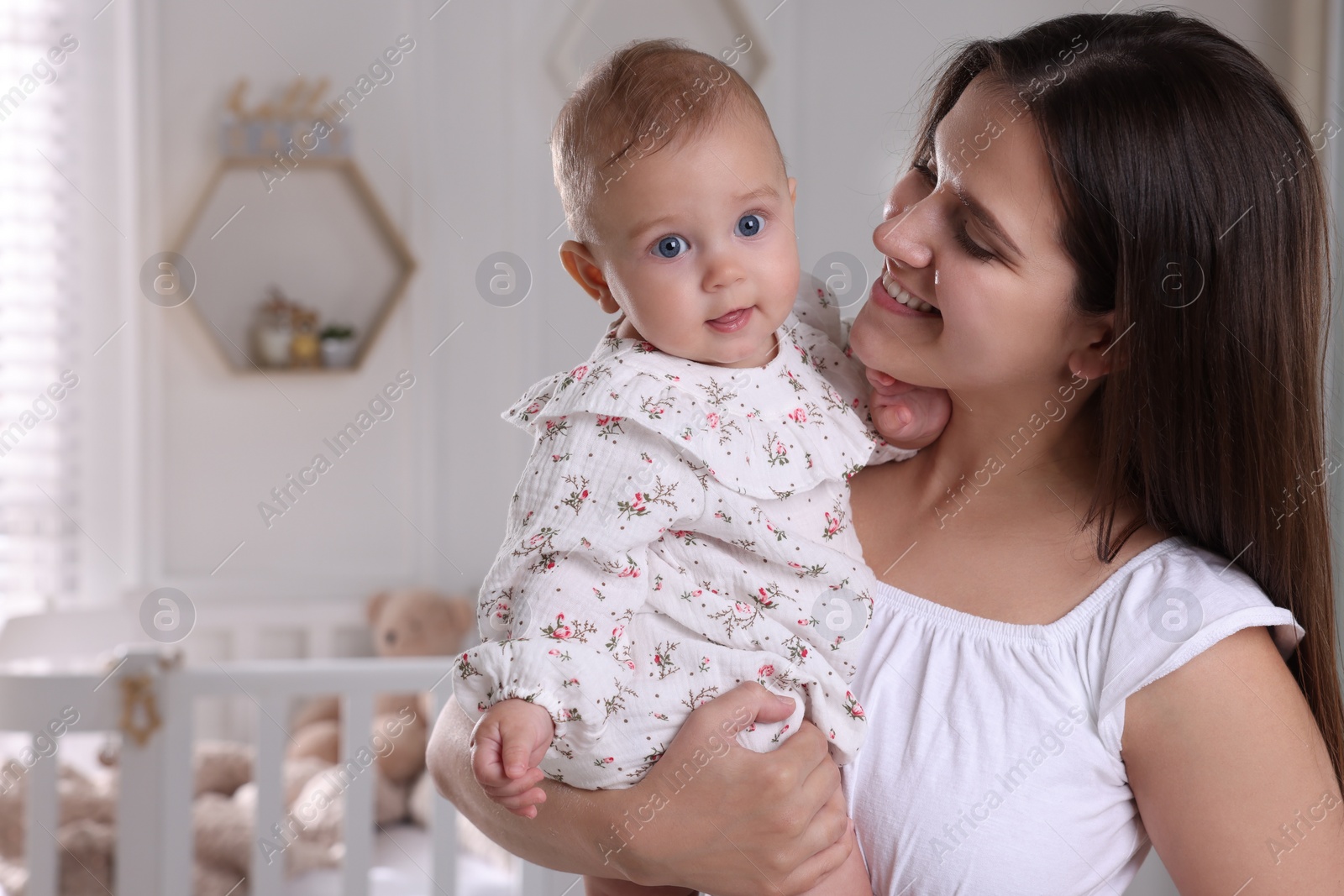 Photo of Happy young mother with her baby daughter in nursery. Space for text