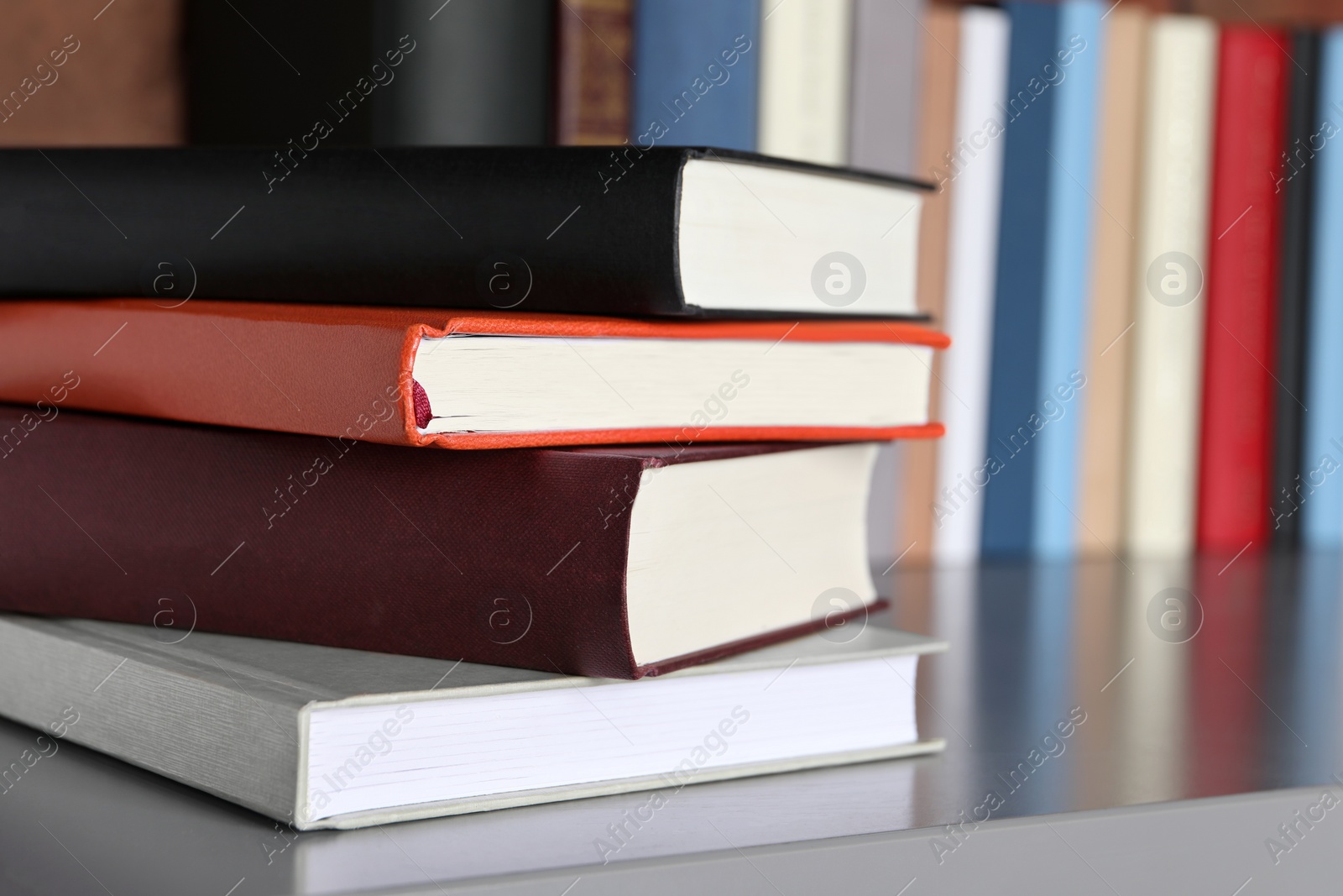 Photo of Stack of hardcover books on grey table indoors, closeup. Space for text