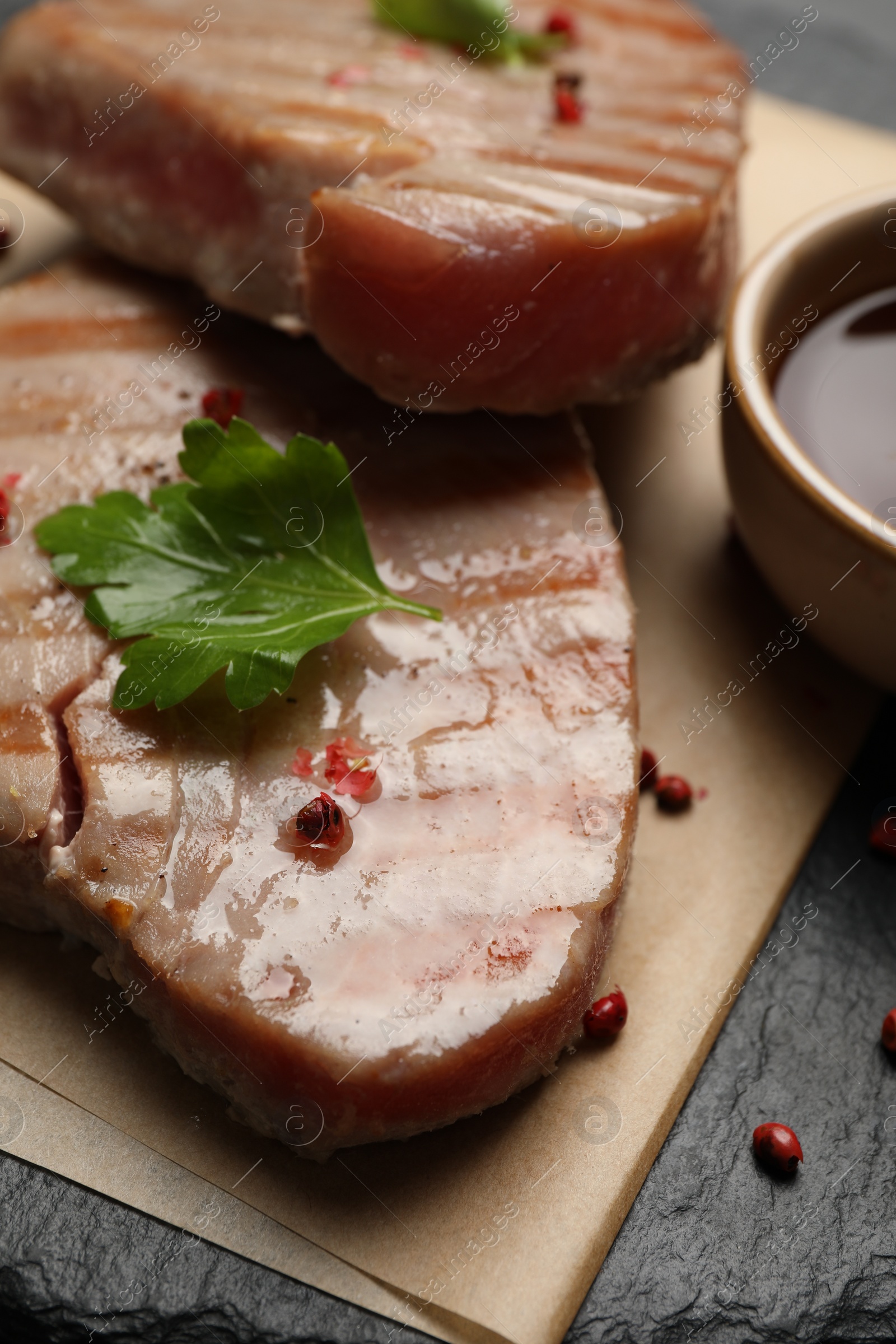 Photo of Delicious tuna steaks with parsley and spices on board, closeup