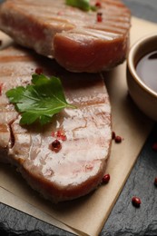 Photo of Delicious tuna steaks with parsley and spices on board, closeup