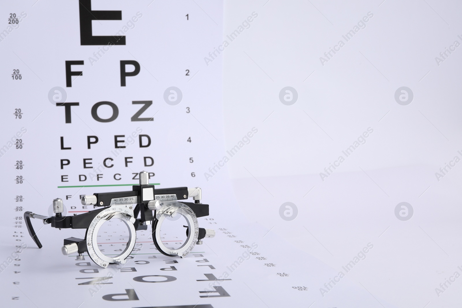 Photo of Vision test chart and trial frame on white background, space for text
