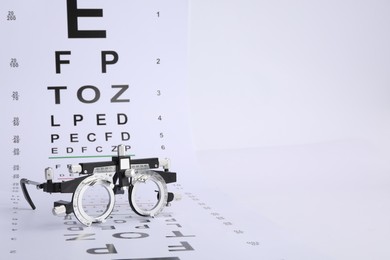 Photo of Vision test chart and trial frame on white background, space for text