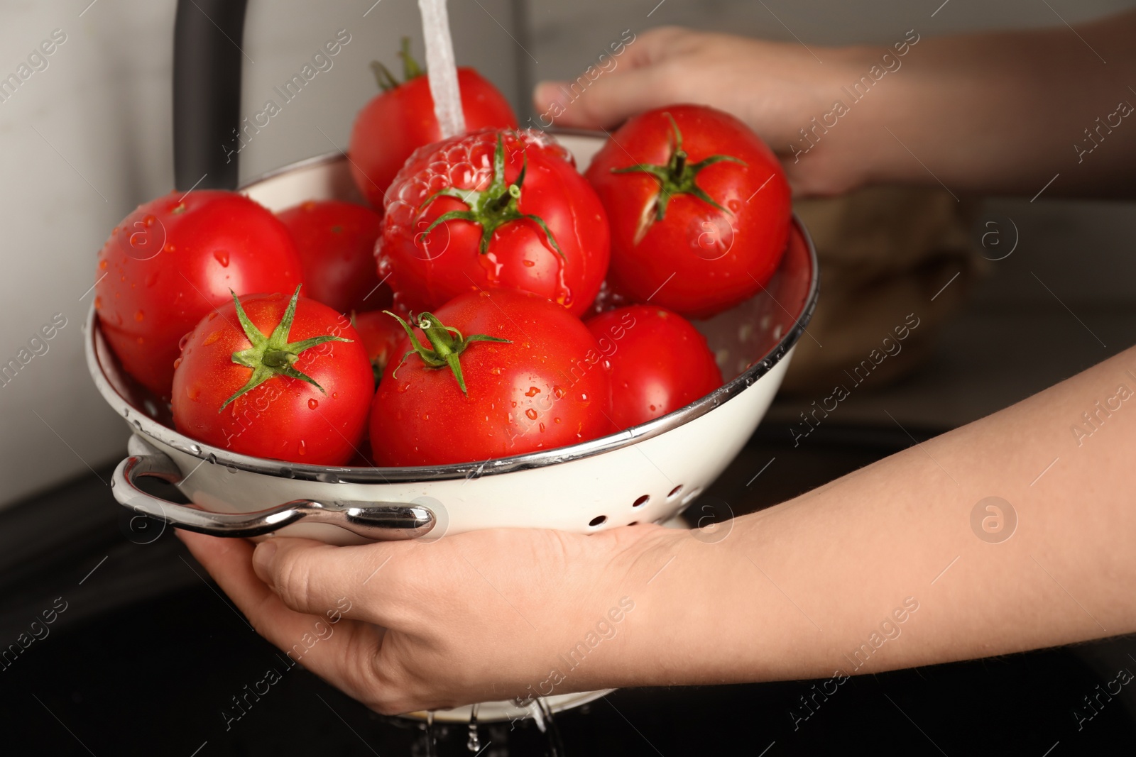 Photo of Woman washing ripe tomatoes in sink, closeup