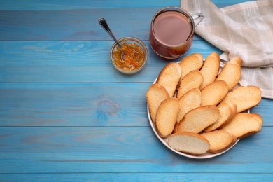 Photo of Hard chuck crackers, jam and cup of tea on light blue wooden table, flat lay. Space for text