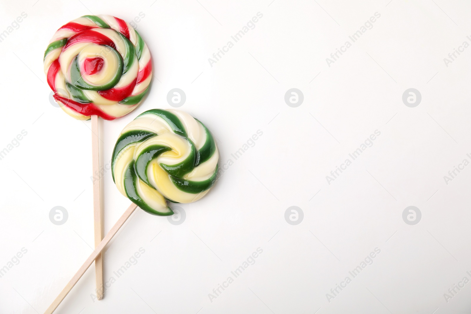 Photo of Colorful lollipops on white background, flat lay. Space for text