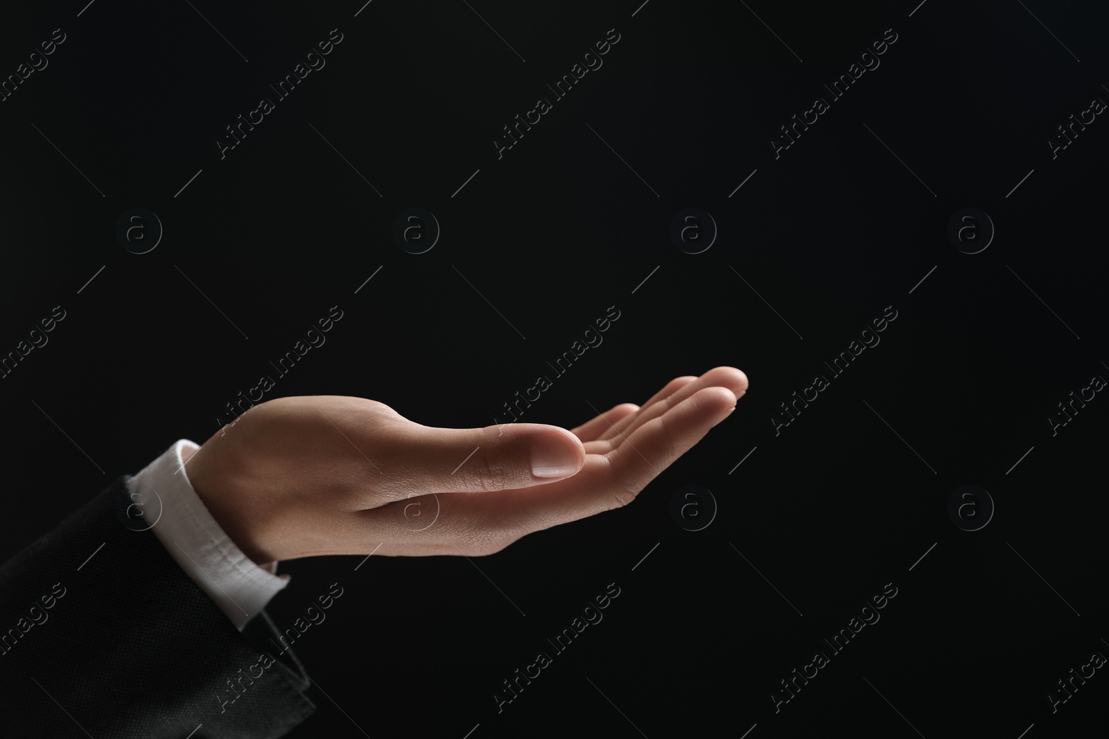 Photo of Man holding something in hand on black background, closeup. Space for text