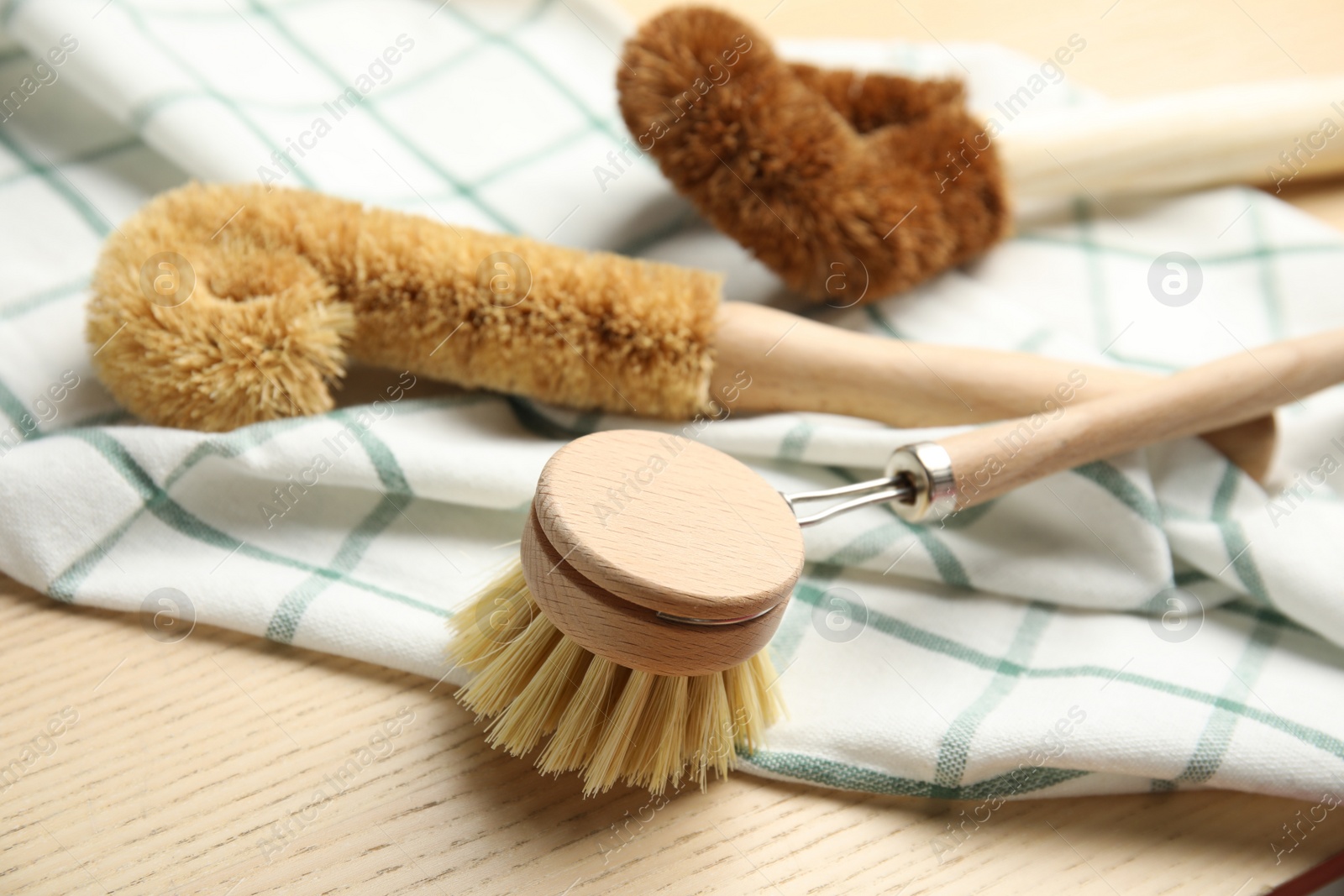 Photo of Cleaning brushes for dish washing on wooden table, closeup