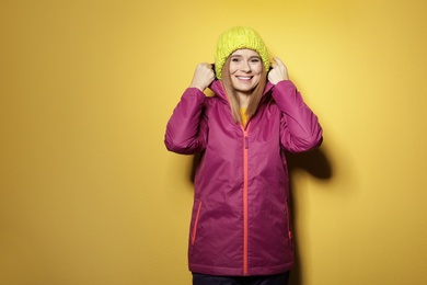 Young woman wearing warm clothes on color background, space for text. Ready for winter vacation