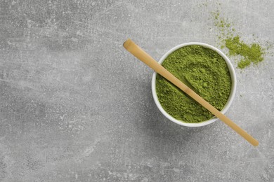 Green matcha powder and bamboo scoop on light grey table, flat lay. Space for text