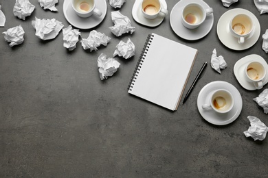 Photo of Empty cups, notebook and crumpled paper on grey table, flat lay. Space for text
