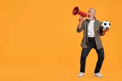 Photo of Emotional senior sports fan with soccer ball using megaphone on yellow background, space for text
