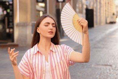 Photo of Woman with hand fan suffering from heat outdoors