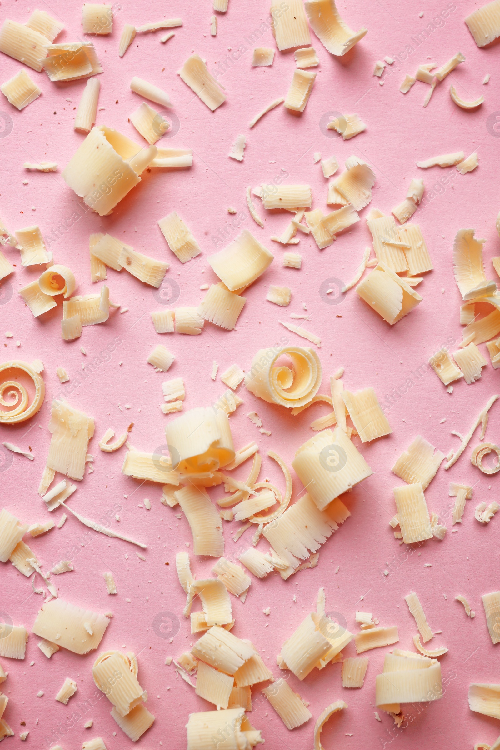 Photo of White chocolate curls on color background, top view