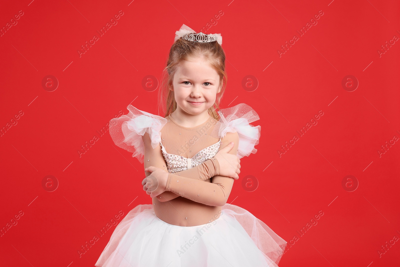 Photo of Cute girl in fairy dress with diadem on red background. Little princess