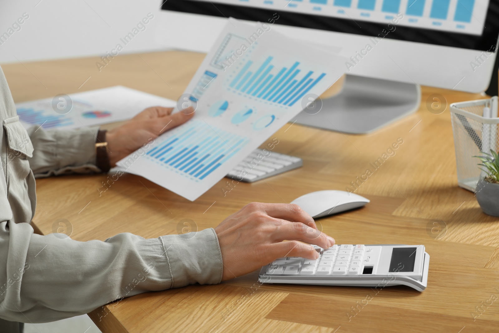 Photo of Professional accountant using calculator at wooden desk in office, closeup