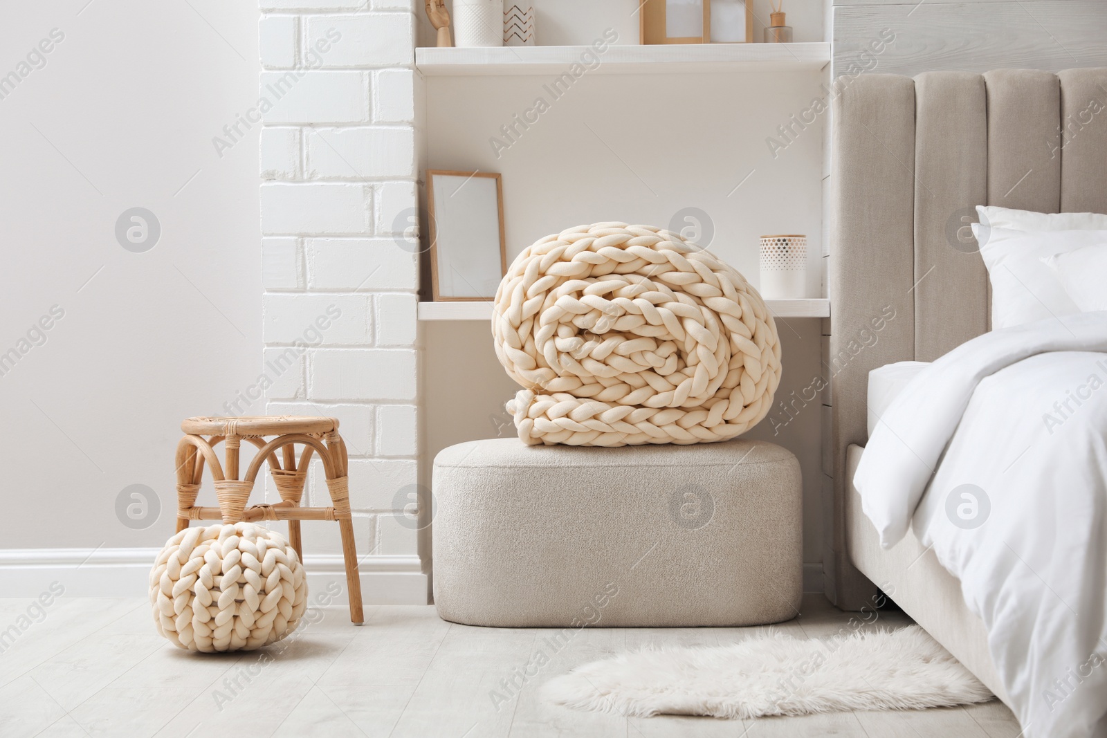 Photo of Soft chunky knit blanket and pouf in stylish room interior