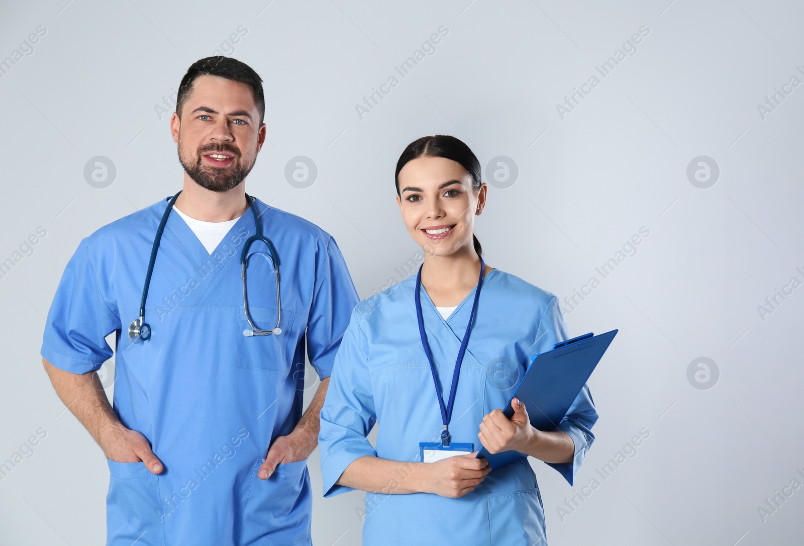 Photo of Mature doctor and young nurse against light background