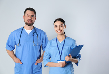 Photo of Mature doctor and young nurse against light background