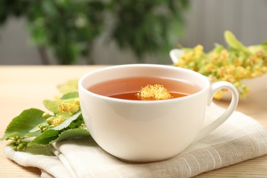 Photo of Cup of tea with linden blossom on wooden table