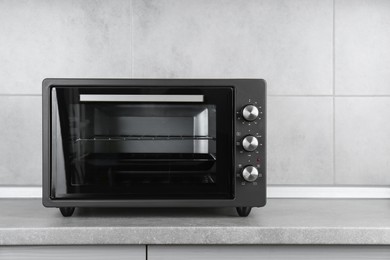 Photo of One electric oven on grey table indoors. Space for text