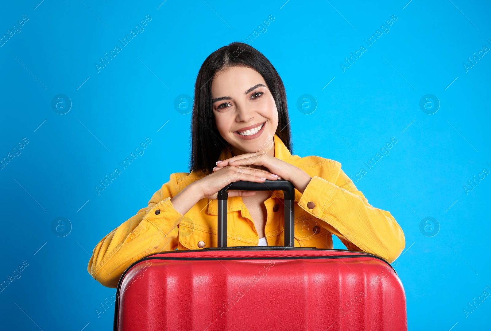 Photo of Beautiful woman with suitcase for summer trip on blue background. Vacation travel