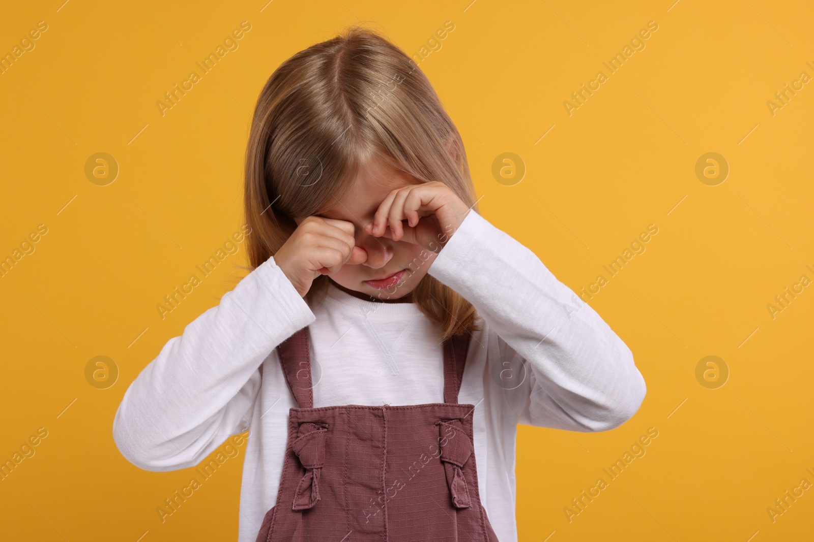 Photo of Resentment. Offensive little girl crying on orange background