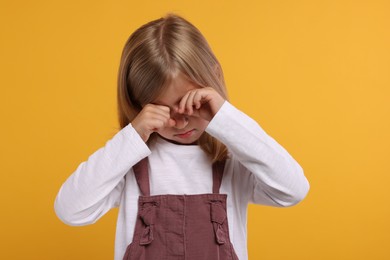 Resentment. Offensive little girl crying on orange background