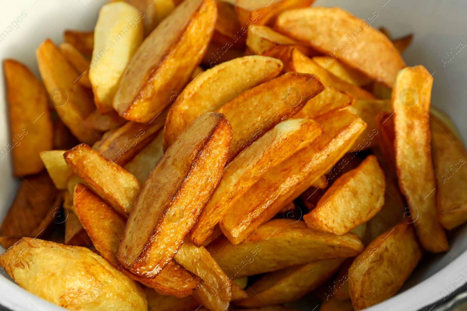 Photo of Metal bowl with delicious fried potato wedges, closeup